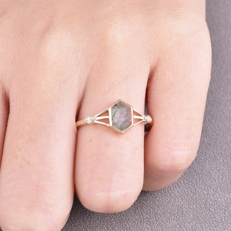 Puede incluir: Un anillo de oro con una piedra preciosa hexagonal verde y gris y dos peque&ntilde;os diamantes a cada lado.