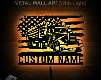 Op de afbeelding: Metalen wandkunst met een zwart silhouet van een houttransportwagen die hout vervoert tegen een achtergrond van een verweerde Amerikaanse vlag. Het kunstwerk heeft een ingebouwde verlichting en een afstandsbediening voor kleur aanpassing. De tekst "CUSTOM NAME" wordt onder de vrachtwagen weergegeven.
