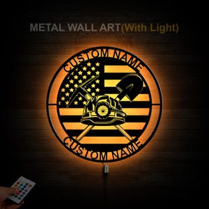 May include: A round metal wall art piece with a lit-up American flag design. The flag has a miner's helmet, pickaxe, and shovel superimposed on it. The words "CUSTOM NAME" are written above and below the flag. The art piece is illuminated with a warm yellow light.