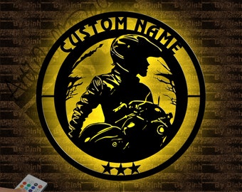 May include: A yellow circle with a black silhouette of a person riding a motorcycle. The circle has the text "CUSTOM NAME" around the top and three stars at the bottom.