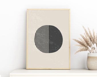 May include: A framed abstract art print featuring a large dark gray circle bisected by vertical black and white lines. The background is a light beige with a textured appearance. The frame is a light wood color.