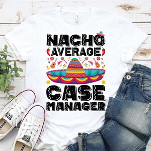 May include: White t-shirt with a black graphic that says "Nacho Average Case Manager" with a sombrero and other festive Mexican-themed designs.