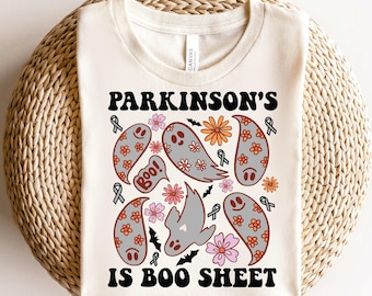 May include: A white t-shirt with a black graphic design that says "Parkinson's is Boo Sheet". The graphic features ghosts, bats, and flowers in shades of orange, pink, and gray.
