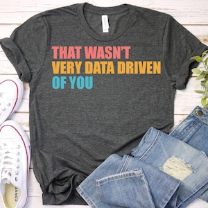 May include: A dark heather gray t-shirt with the text "THAT WASN'T VERY DATA DRIVEN OF YOU" in colorful letters.
