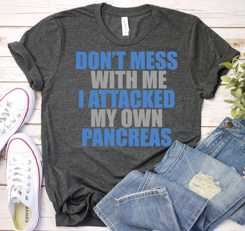 May include: A dark heather grey t-shirt with the text "Don't mess with me I attacked my own pancreas" in blue and grey lettering.