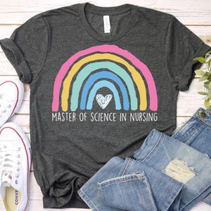 May include: A dark gray t-shirt with a rainbow design and the text "Master of Science in Nursing". The rainbow has a heart in the center.