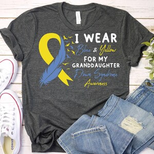 May include: Gray t-shirt with a blue and yellow ribbon, a blue feather, and the text "I wear blue & yellow for my granddaughter Down Syndrome Awareness".