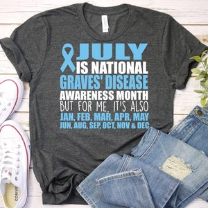May include: A dark gray t-shirt with a blue ribbon and the text "JULY IS NATIONAL GRAVES' DISEASE AWARENESS MONTH BUT FOR ME, IT'S ALSO JAN, FEB, MAR, APR, MAY JUN, AUG, SEP, OCT, NOV & DEC"