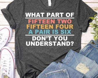 May include: A dark grey t-shirt with the text "WHAT PART OF FIFTEEN TWO FIFTEEN FOUR A PAIR IS SIX DON'T YOU UNDERSTAND?" printed in colourful letters.