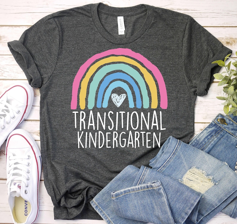May include: A dark gray t-shirt with a rainbow and heart design. The text "Transitional Kindergarten" is printed below the rainbow.