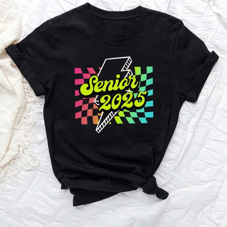 May include: Black t-shirt with a rainbow checkered design and a lightning bolt graphic. The text "Senior 2025" is written in yellow with a retro font.