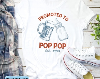May include: White t-shirt with a blue and red graphic that says "Promoted to Pop Pop Est. 2024". The graphic features a beer mug and a baby bottle.