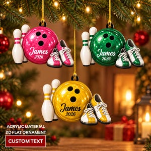 May include: Three flat acrylic Christmas ornaments featuring bowling themes in pink, green, and yellow. Each ornament displays a bowling ball, two pins, and a pair of bowling shoes with the custom text James 2026 printed on the ball.