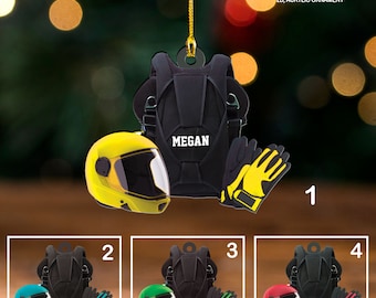 Può includere: Un ornamento acrilico nero raffigurante un paracadute con il nome "MEGAN", un casco giallo e guanti neri con dettagli gialli. L'ornamento include anche il testo "custom text" e "2D, ACRYLIC ORNAMENT".