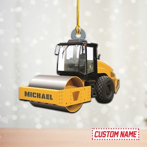 May include: Yellow and black construction vehicle ornament with a roller and the name "MICHAEL" on the side.