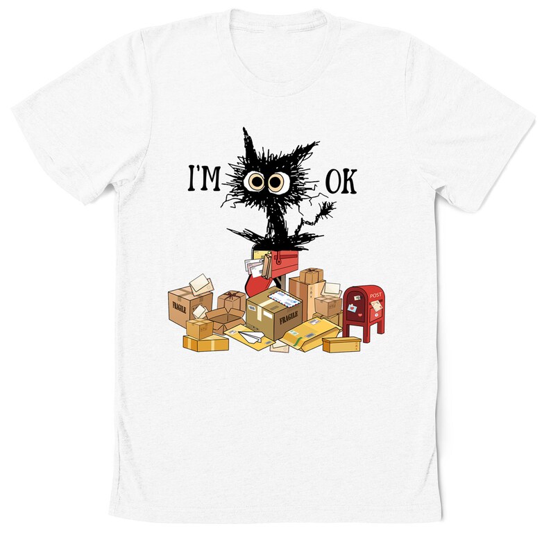 May include: White t-shirt with a black cartoon cat surrounded by boxes and mail. The cat has large eyes and the text "I'M OK" above it.