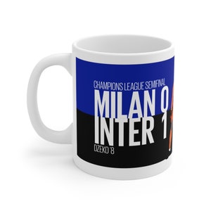 Könnte beinhalten: Weiße Keramiktasse mit blauem und schwarzem Design. Der Text auf der Tasse lautet "Champions League Semifinal Milan 0 Inter 1 Dzeko '8".
