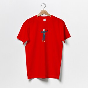 以下が含まれることがあります： 筋肉を誇示する人物の漫画イラストが描かれた赤いTシャツ
