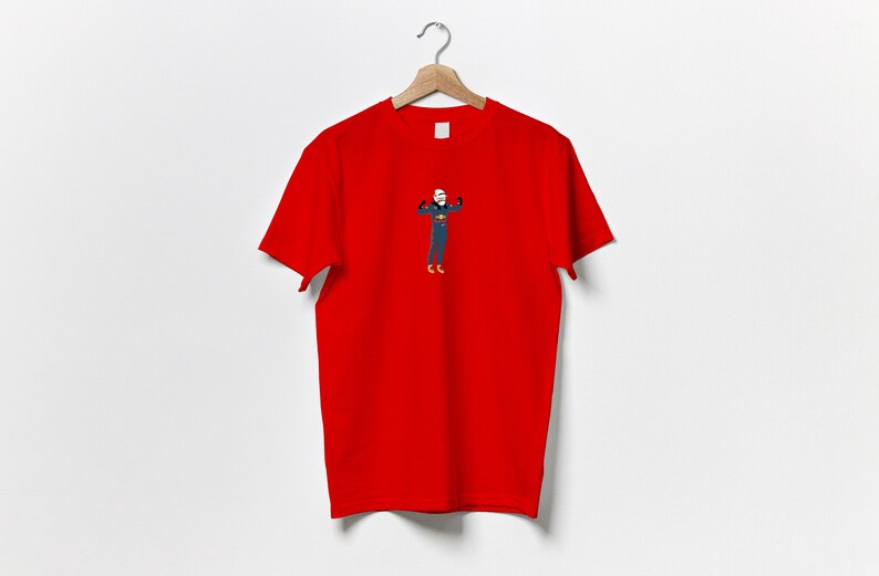 以下が含まれることがあります： 筋肉を誇示する人物の漫画イラストが描かれた赤いTシャツ