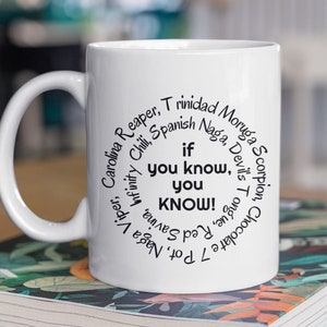 May include: White ceramic mug with a black circle of text that reads "If you know, you know!"  The text is surrounded by a list of chili pepper names, including "Trinidad Moruga Scorpion", "Carolina Reaper", "Spanish Naga", "7 Pot", "Naga Viper", "Infinity Chili", "Chocolate 7 Pot", "Devil's Tongue", "Savina", "Red Savina", "Habanero", and "Scotch Bonnet".