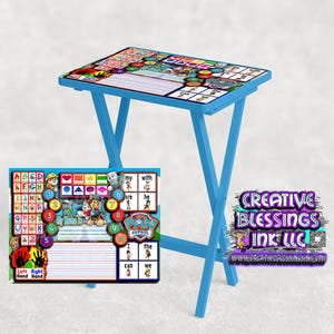 May include: A blue folding table with a Paw Patrol themed learning activity printed on the surface. The activity includes letters, numbers, shapes, and a section for writing. The table is set up for a child to use.