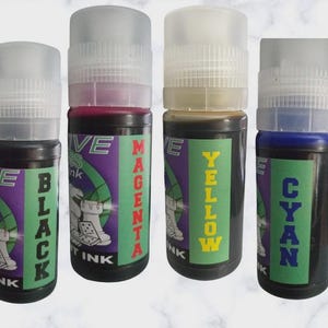 May include: Four ink bottles labeled Black, Magenta, Yellow, and Cyan. Each bottle has a clear cap and a label with the ink color name in large letters. The labels also include the text "INK" and a graphic design.