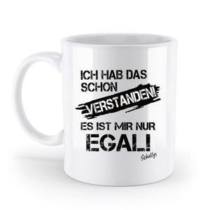 Könnte beinhalten: Weiße Keramiktasse mit schwarzem Text, der "Ich hab das schon verstanden! Es ist mir nur egal!" lautet und die Unterschrift "Schollys" am Boden.