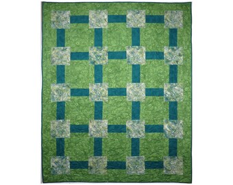 Batik wildflowers in greens and teal evoke a sense of calm and peace found when walking in nature in this lap quilt or wall hanging.