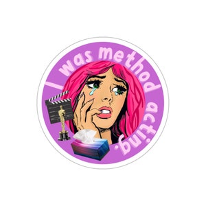 May include: A purple circle sticker with the text "I was method acting." A cartoon woman with pink hair is crying. She is holding a tissue box and an Oscar statuette. There is a clapperboard behind her.
