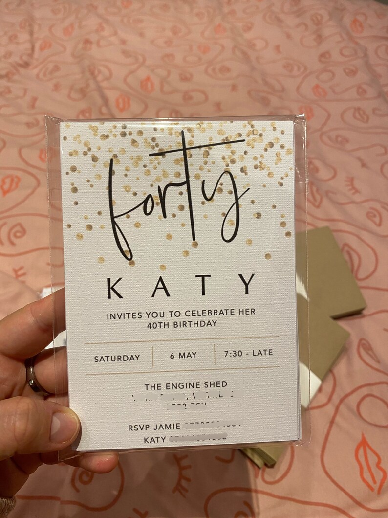 Puede incluir: Una tarjeta de invitaci&oacute;n blanca con detalles de purpurina dorada. El texto de la tarjeta dice "forty" en letra cursiva, seguido de "KATY" en may&uacute;sculas. La invitaci&oacute;n es para la fiesta de cumplea&ntilde;os n&uacute;mero 40 de Katy, que se celebrar&aacute; el s&aacute;bado 6 de mayo a las 7:30 PM en The Engine Shed. RSVP a Jamie.