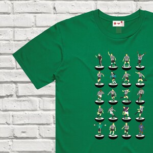 Puede incluir: Una camiseta verde con un dise&ntilde;o de 24 jugadores de f&uacute;tbol con uniformes negros y blancos sobre un fondo blanco. Los jugadores est&aacute;n dispuestos en cuatro filas de seis jugadores cada una. Cada jugador est&aacute; de pie sobre un c&iacute;rculo blanco y negro.