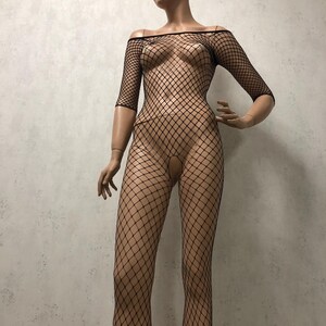 May include: Black fishnet bodysuit with an off-the-shoulder neckline and three-quarter sleeves. The one-piece garment features a diamond-shaped mesh pattern and is displayed on a mannequin.