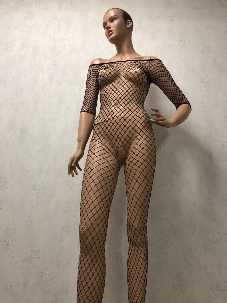 May include: Black fishnet bodysuit with an off-the-shoulder neckline and three-quarter sleeves. The one-piece garment features a diamond-shaped mesh pattern and is displayed on a mannequin.
