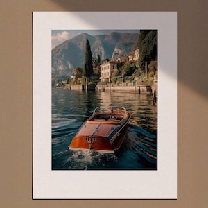 May include: A wooden motorboat glides across a lake, leaving a wake. The boat has a classic design with a curved windshield and a polished wooden deck. The background features a mountain range, buildings, and trees.
