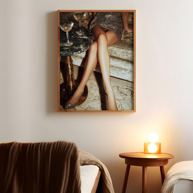 Puede incluir: Una impresi&oacute;n enmarcada que presenta una escena glamurosa. La imagen muestra a una persona con un vestido brillante, sentada cerca de una peque&ntilde;a mesa con copas de champ&aacute;n. La atenci&oacute;n se centra en las piernas y los tacones altos, creando una sensaci&oacute;n de lujo y elegancia. La impresi&oacute;n est&aacute; en un marco de madera.
