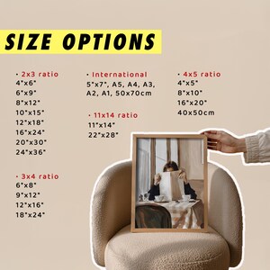 May include: A framed art print featuring a person reading at a table, with a neutral color palette. The print is displayed on a cream-colored chair. Text on the image reads "SIZE OPTIONS" with various size ratios and dimensions.