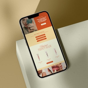 以下が含まれることがあります： リップグロス製品のウェブサイトを表示している携帯電話。ウェブサイトには、リップグロスを塗っている人の写真、製品の説明、そして自分にぴったりの色を見つけるためのセクションが掲載されています。ウェブサイトには、今すぐ購入するための行動喚起も含まれています。