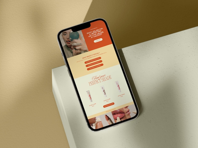 以下が含まれることがあります： リップグロス製品のウェブサイトを表示している携帯電話。ウェブサイトには、リップグロスを塗っている人の写真、製品の説明、そして自分にぴったりの色を見つけるためのセクションが掲載されています。ウェブサイトには、今すぐ購入するための行動喚起も含まれています。