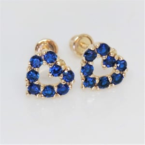 May include: A pair of gold heart-shaped earrings with blue gemstones.