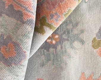 May include: Close-up of a patterned rug with a light blue background and pink, green, and blue designs. The rug has a soft, textured surface.