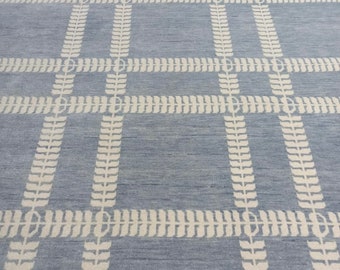 May include: A light blue rug with a white geometric pattern of leaves. The rug has a subtle texture and a woven look.