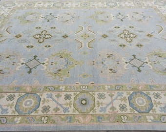 May include: A light blue rug with a traditional Persian design. The rug has a light green and cream border with intricate floral patterns.