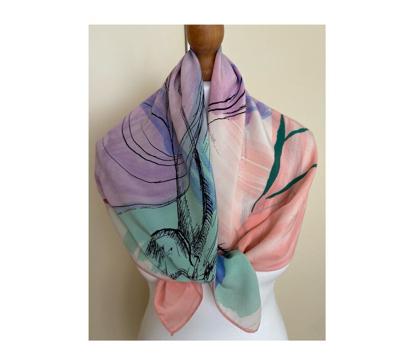 Puede incluir: Una bufanda de seda rosa, verde y morada con un dise&ntilde;o abstracto. La bufanda est&aacute; atada alrededor del cuello de un maniqu&iacute;.