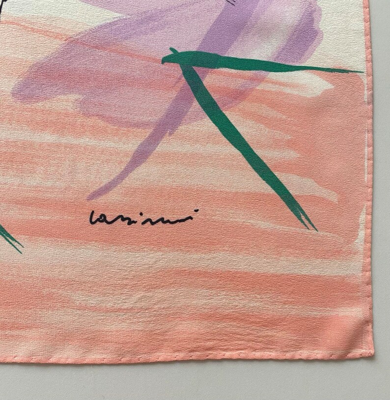 Puede incluir: Una bufanda de seda rosa con un dise&ntilde;o abstracto en verde y morado. La bufanda est&aacute; firmada "lazimini" en la esquina inferior derecha.