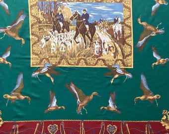 May include: A green scarf featuring a hunting scene within a gold frame, with flying ducks scattered around. The scarf has a red border with gold details. The ducks are brown and blue. The hunting scene shows riders on horseback with hounds.