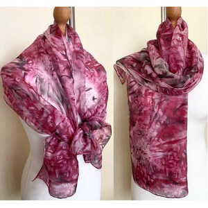 May include: A pink and gray silk scarf with a floral pattern. The scarf is draped over a mannequin.