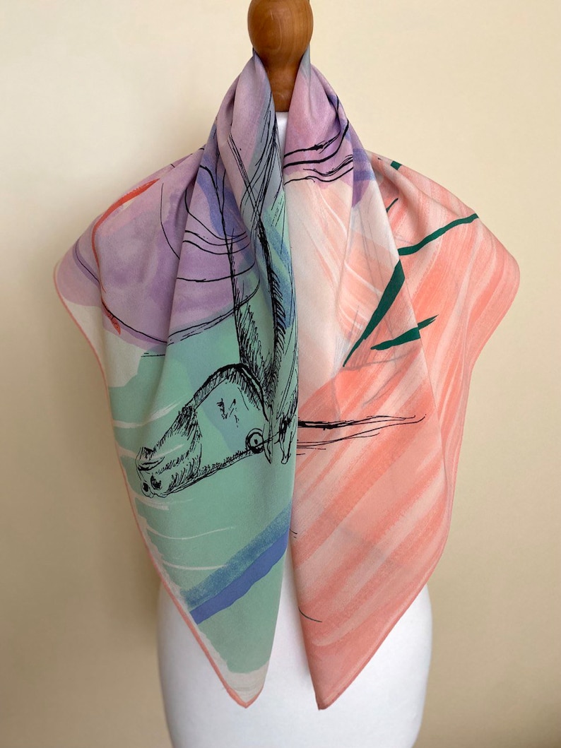 Puede incluir: Un pa&ntilde;uelo de seda cuadrado con un dise&ntilde;o abstracto colorido. El pa&ntilde;uelo presenta un dibujo de un caballo en tinta negra, con lavados de acuarela rosa, verde, azul y morado en el fondo.