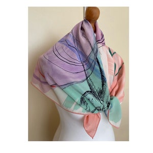 Puede incluir: Una bufanda de seda rosa, verde y morada con un dise&ntilde;o abstracto en blanco y negro. La bufanda est&aacute; atada alrededor del cuello de un maniqu&iacute;.