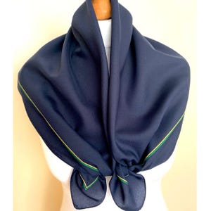 May include: A navy blue scarf with a thin yellow and green trim around the edges.