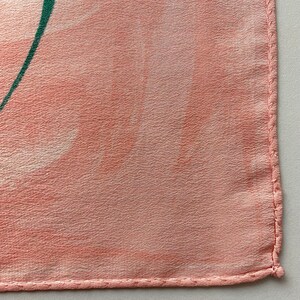 Puede incluir: Primer plano de una tela rosa con un dise&ntilde;o verde. La tela tiene una superficie texturizada y est&aacute; bordeada con una costura cosida.